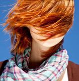 Portrait of red-haired girl with scarf on blue background.