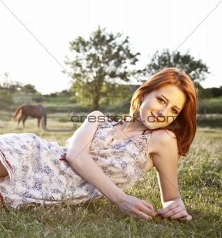 Girl at green grass field at sunset. 