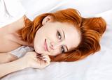 Pretty red-haired sleeping woman in white nightie lying in the b