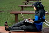 Malay female teen with laptop and headphones outside