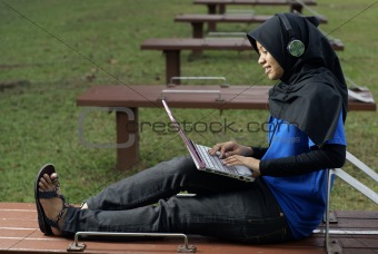 Malay female teen with laptop and headphones outside