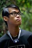 Slick hair asian man with spectacles outdoors looking away 
