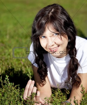 Portrait of beautiful brunette girl with blue eyes on green grass