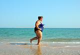 overweight woman running on beach