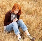 Lonely sad red-haired girl in field