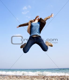 Young beautiful girl jumping at the beach.