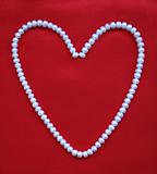 Heart from white pearls on a red silk for St Valentine's day 