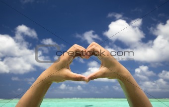 hand forming a heart on tropical beach background