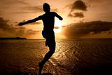 silhouette of boy jumping to the sea at  sunset