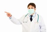Medical doctor in mask pointing  finger up in corner at copy space
