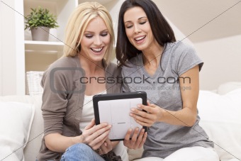 Two Young Women Using Tablet Computer At Home on Sofa