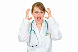 Shocked medical female doctor holding her hands near head
