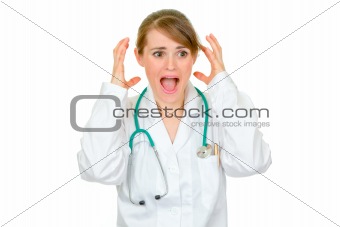 Shocked medical female doctor holding her hands near head
