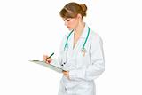 Concentrated medical female doctor making notes in document
