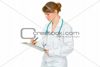 Concentrated medical female doctor making notes in document
