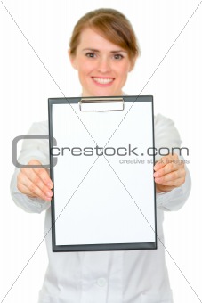 Smiling medical female doctor holding blank clipboard in hands
