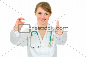 Smiling female doctor holding medical thermometer and showing thumbs up gesture
