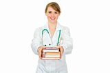 Smiling young female doctor giving several books
