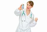 Pleased medical female doctor holding calculator in hand and showing yes gesture
