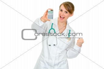 Pleased medical female doctor holding calculator in hand and showing yes gesture
