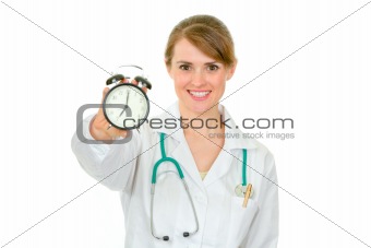 Smiling medical female doctor holding alarm clock in hand
