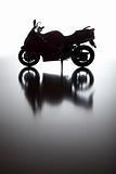 Silhouette of Street Motorcycle on Reflective Surface Against a White Background.