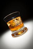 Glass of Whiskey or Other Alcoholic Drink and Ice Under Spot Light.