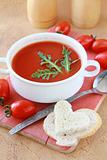 tomato soup in a white bowl with arugula and cherry tomatoes