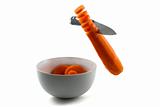 Knife chopping carrot slices into white bowl