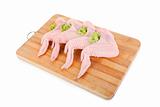 Raw chicken wings with green salad on wooden board 