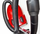The red vacuum cleaner with a black hose on a white background
