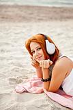 Portrait of red-haired girl with headphone at beach.