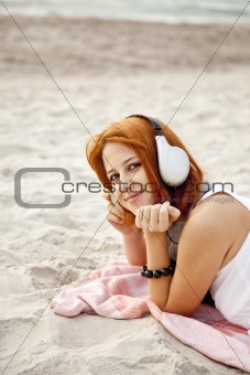 Portrait of red-haired girl with headphone at beach.