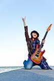 Young red-haired girl play on guitar at windy day.