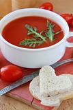 tomato soup in a white bowl with arugula and cherry tomatoes