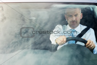 businessman driving car with sky reflections on windshield