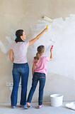 Mother and daughter painting a wall with roller