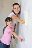 Mother and douther painting a wall with roller