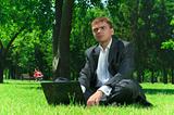 Businessman in a park on the grass wiht laptop
