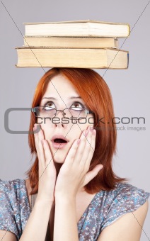 Red-haired girl keep books on her head. Studio shot.