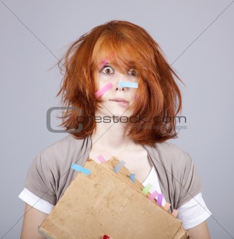 Red-haired businesswoman with book and notes on face. 
