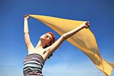 Young woman with open arms keep yellow silk on wind.