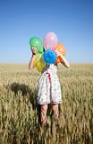 Girl with balloons at wheat field