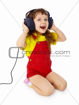 Little girl sitting on white with large earpieces
