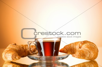 Tea and croissants on the reflective background