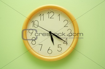 Yellow wall clock on the green