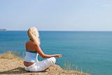 Girl meditating in the lotus position on the sea