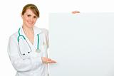 Smiling  medical doctor woman pointing on blank billboard
