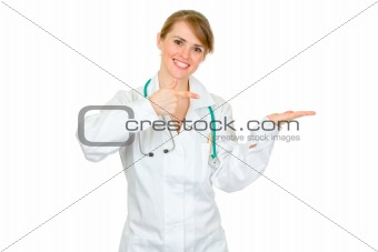 Smiling female medical doctor pointing finger on empty hand
