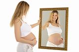 pregnant woman looks in the mirror